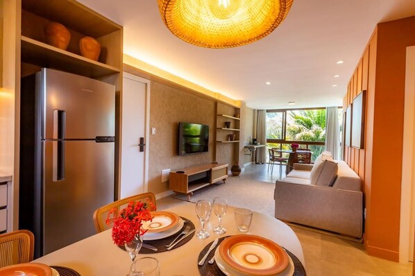 Een moderne woonkamer met een eethoek, een flatscreen televisie en een balkon met tuinmeubilair.