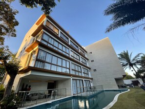 Un hôtel à plusieurs étages doté d’une piscine, de grandes fenêtres et d’une architecture moderne.