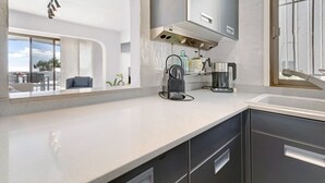 Een moderne keuken met een groot raam, roestvrijstalen apparatuur en een minimalistisch design.