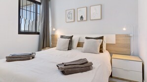 Een keurig opgemaakt bed met handdoeken, een nachtkastje en wanddecoratie.