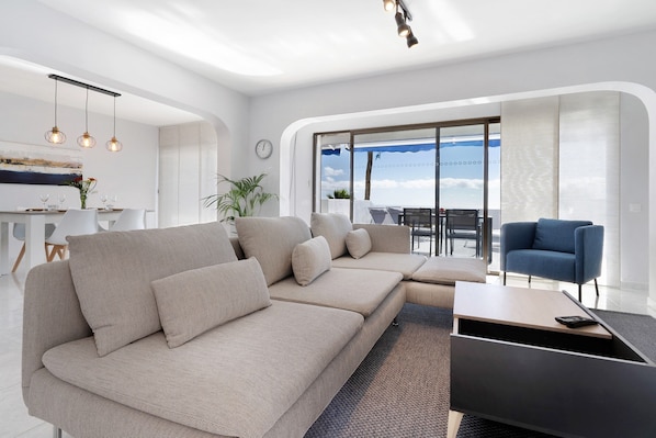 A modern living room with a sectional sofa, a coffee table, and a view of the outdoors.