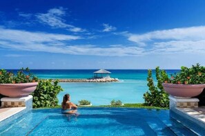 A pool with a view of the ocean and a small island with a gazebo. - Luxury 1-bed Apartment in Montego Bay (Montego Bay)