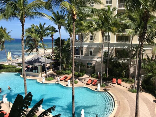 A resort with a swimming pool, palm trees, and a view of the ocean. - Luxury 1-bed Apartment in Montego Bay (Montego Bay)