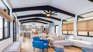 Un vaste espace de vie doté d’un plafond haut, de poutres en bois et d’une grande fenêtre.