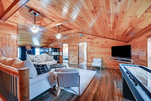 A cozy wooden cabin interior with a sofa, armchair, and foosball table.