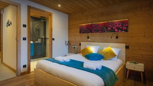 Quarto com painéis de madeira, uma cama, uma mesa de cabeceira e uma obra de arte na parede.