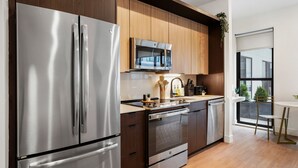 Une cuisine moderne dotée d’appareils électroménagers en acier inoxydable, de meubles en bois et offrant une vue sur l’extérieur.