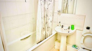 A bathroom with a bathtub, a sink, and a toilet. - Peaceful Impeccable 2-bed Apartment in Hatfield (Hatfield)