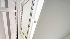 A modern interior with a white staircase, metal railings, and a ceiling with a geometric design. - Immaculate 2-bed Apartment in Welwyn Garden City (Welwyn Garden City)