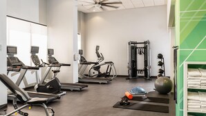 A gym with treadmills, elliptical machines, a stationary bike, a weight machine, and a yoga mat area. - South Country Suites (Mesa)