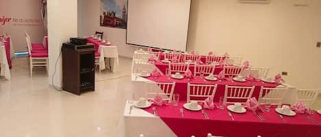 A conference room with tables set for a meeting, a podium, and a projection screen.