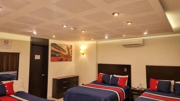 A hotel room with three beds, a ceiling with recessed lighting, an air conditioning unit, and a painting on the wall.