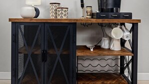 Ein Küchenbereich mit einem Holztisch, einer Kaffeemaschine und zwei gerahmten Kunstwerken mit Blättern an der Wand.