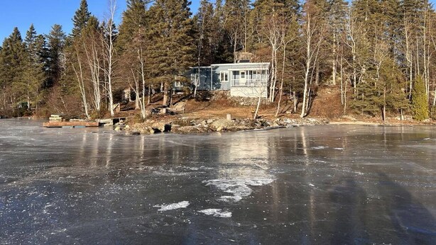 A house by a frozen lake with a dock and a small bridge. - Chalet Rustique sur île (Saguenay)