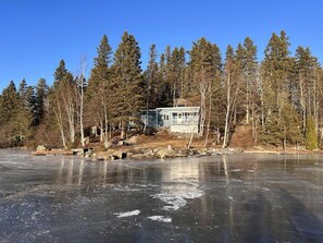 A house by a frozen lake with a dock and a small bridge.