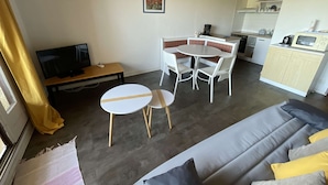 A compact living space with a sofa, a dining table with chairs, a kitchen area, and a television. - Seignosse Ocean,  with a parking space, near beach, 4 pers. ideal family (SEIGNOSSE)