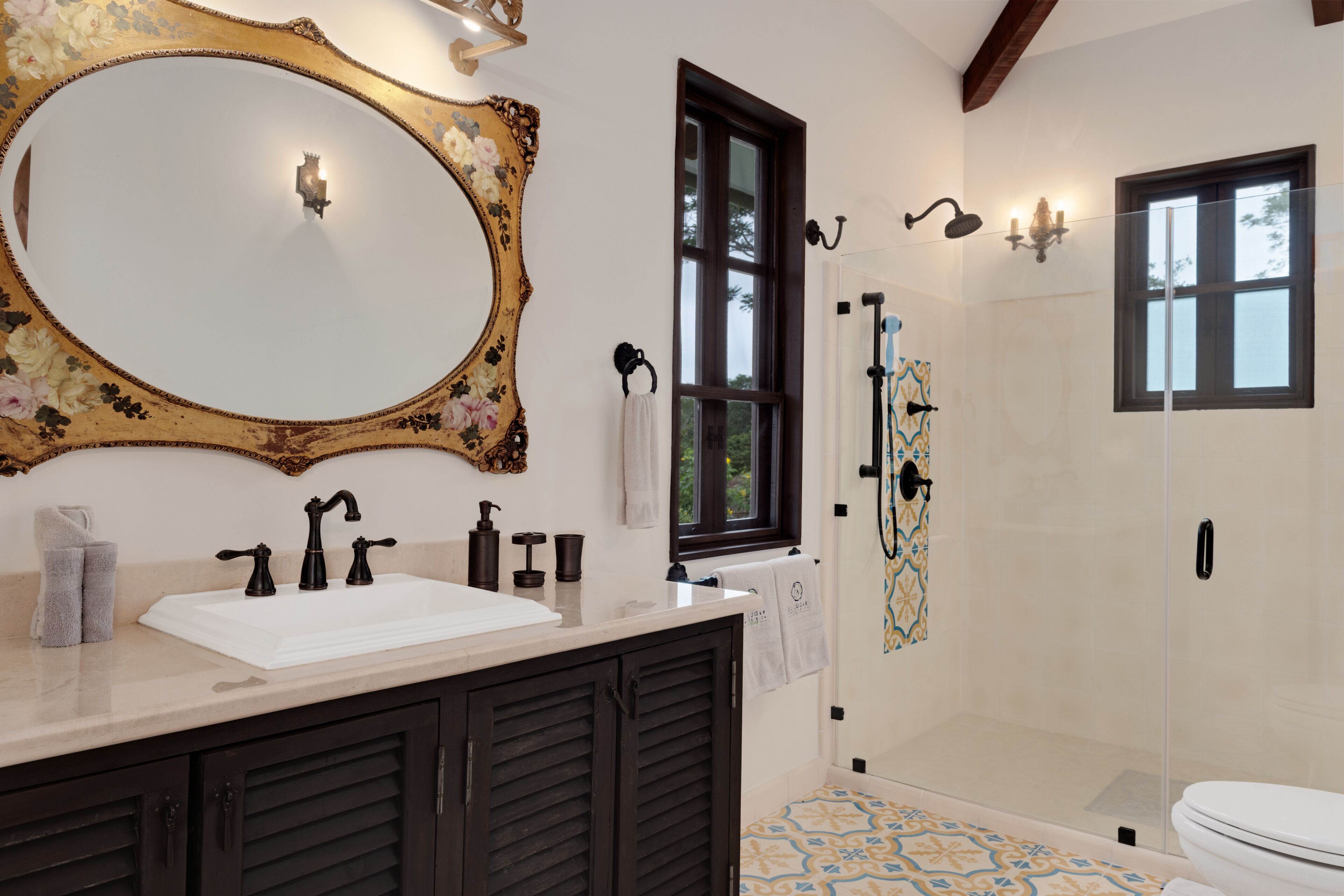 Un baño con un espejo grande, un lavabo, una ducha y un inodoro.
