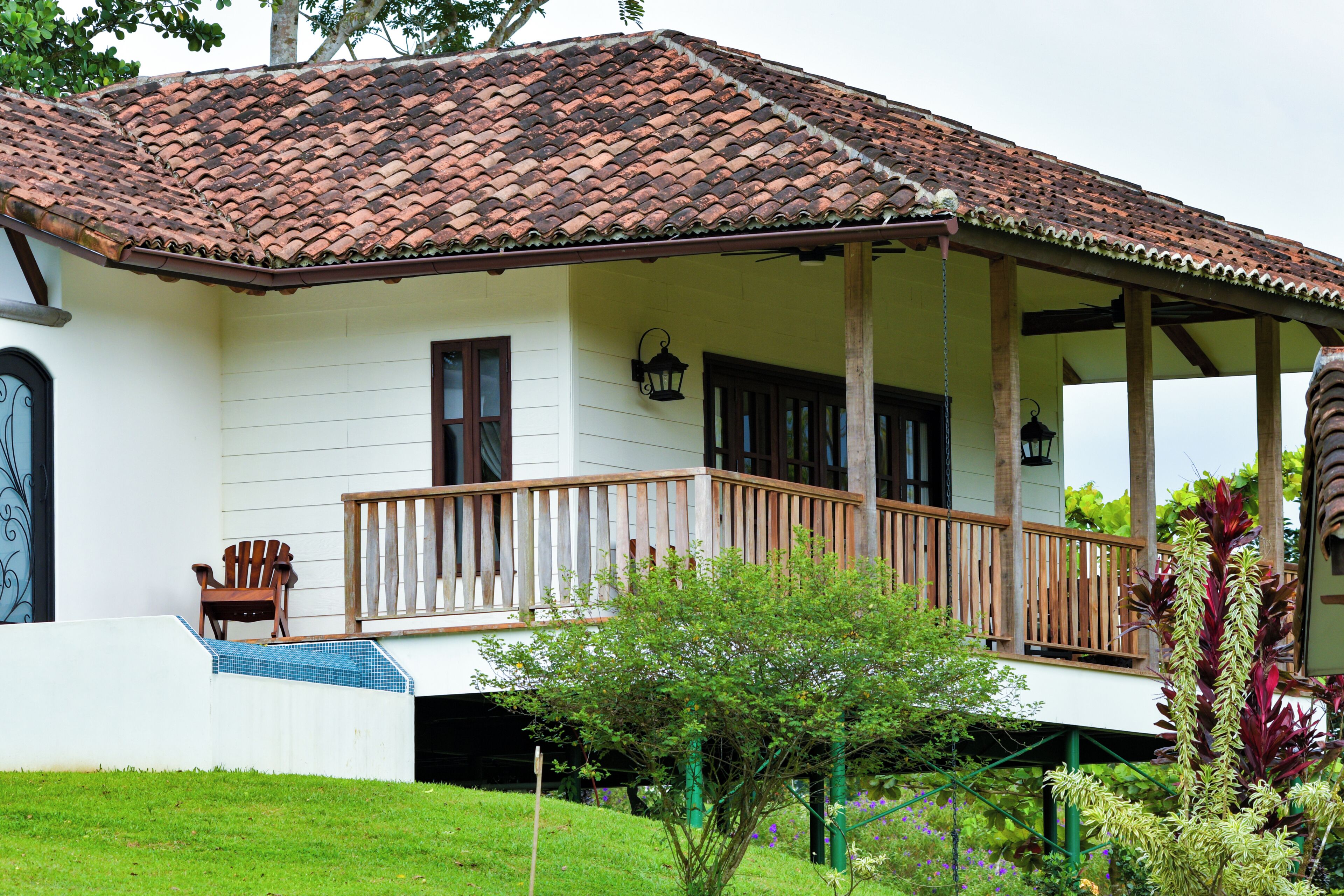 A house with a tiled roof, a wooden porch, and a small garden area.