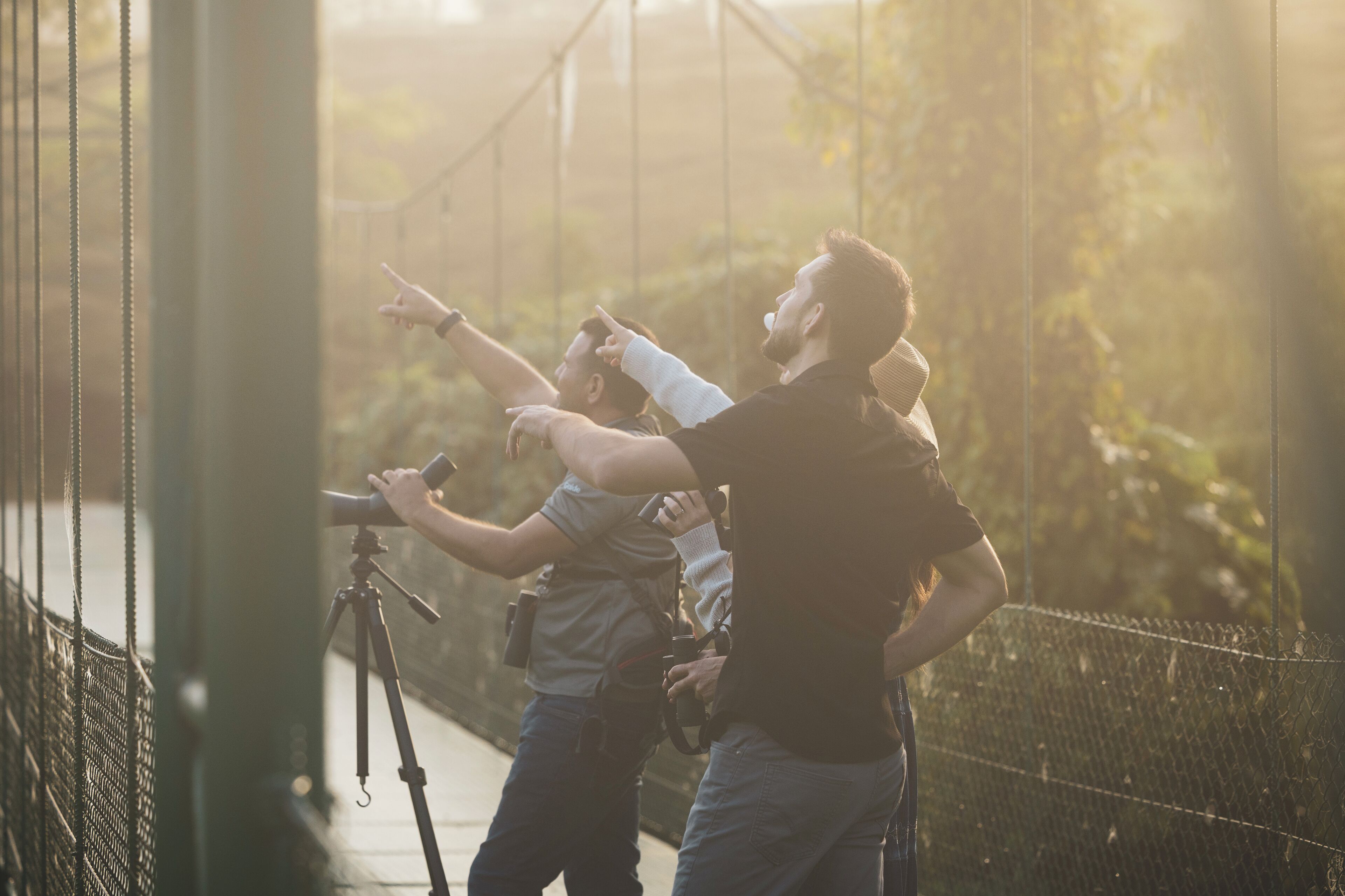 A person using a camera on a tripod on a bridge.