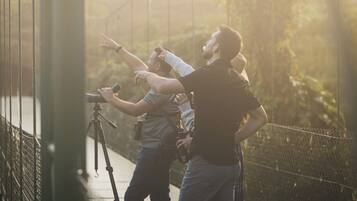 A person using a camera on a tripod on a bridge.