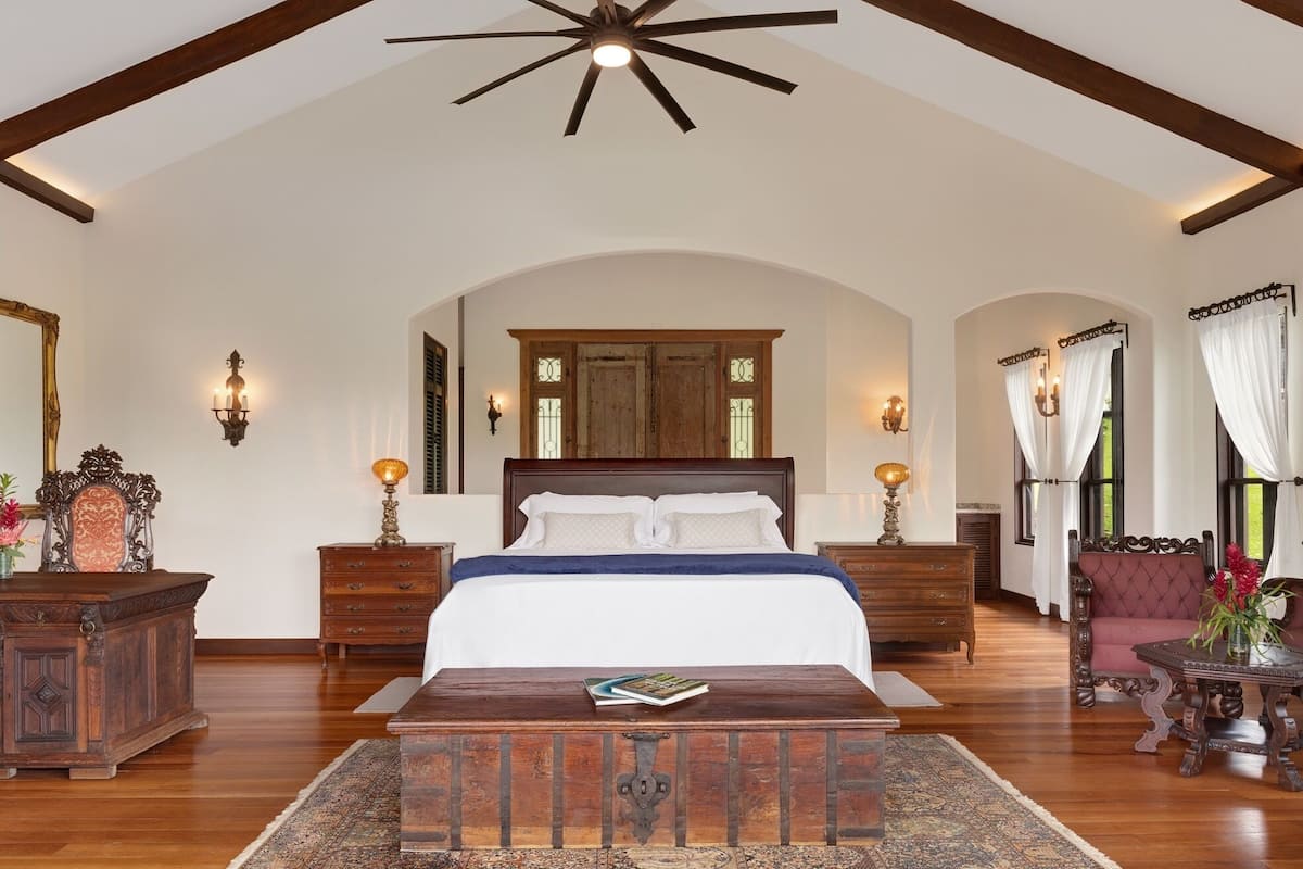 A spacious bedroom with a large bed, wooden headboard, and a ceiling fan.