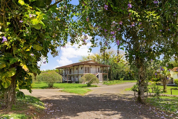 A two-story building with a balcony, surrounded by greenery and a gravel path. - El Lugar Hotel & Nature Reserve Costa Rica (Las Horquetas)