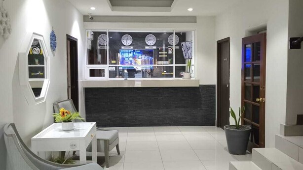 Una moderna zona de recepción con mostrador, asientos y un amplio ventanal que muestra relojes.