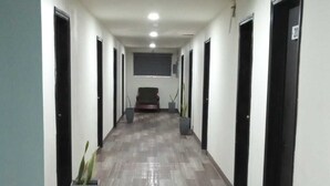 Un pasillo con piso estampado, puertas negras y plantas en macetas.