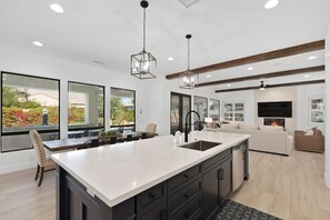 A modern kitchen with a large island, dark cabinetry, and pendant lighting.