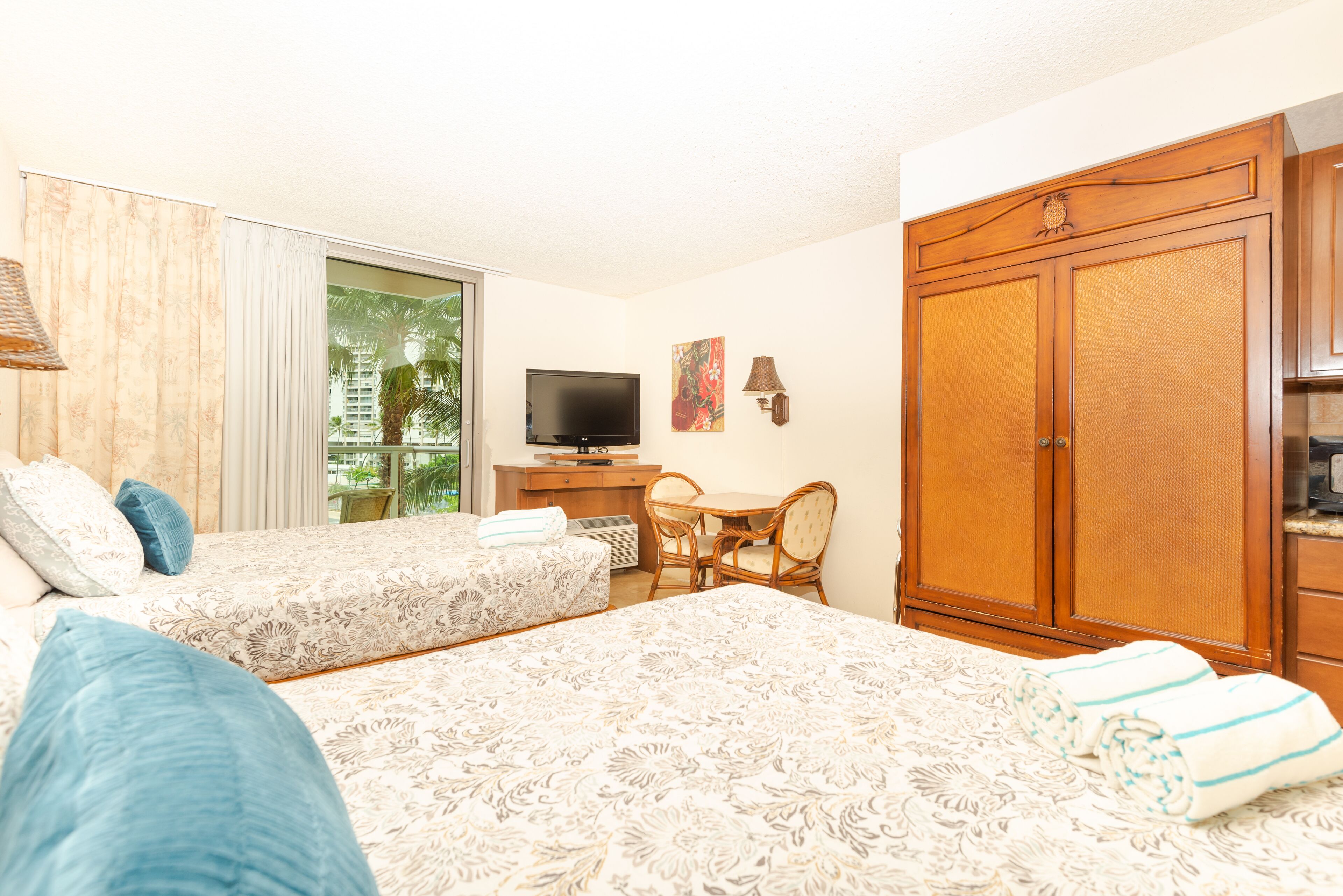 A hotel room with two beds, a television, a desk with a chair, and a wardrobe.