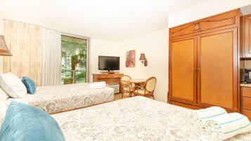 A hotel room with two beds, a television, a desk with a chair, and a wardrobe.