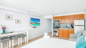 A modern kitchen with wooden cabinets, a microwave, and a refrigerator. - Newly Updated*Free Parking*Full Kitchen*Close to Beach (Honolulu)