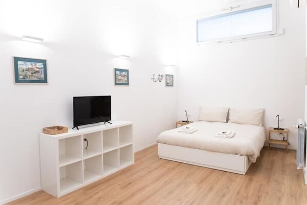 Relax in a serene bedroom with a flat-screen TV, large bed, and bedside table.