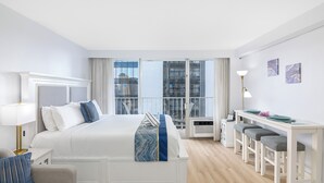 Een moderne hotelkamer met een groot bed, een bureau met een stoel en stadszicht door grote ramen.