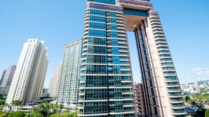 A modern high-rise building with a curved facade, multiple balconies, and a glass exterior.