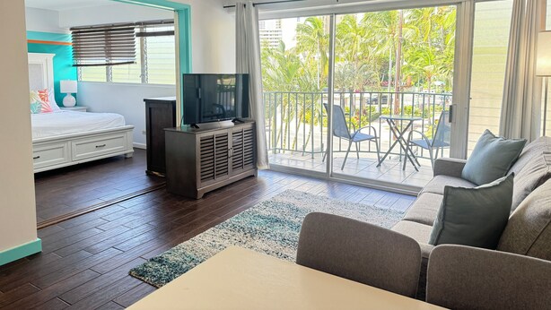 Una habitación de hotel moderna con balcón, cama, televisor y sofá.