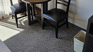 A small, neatly arranged room with a round table and two chairs, a lamp, and a trash bin. - Recently Renovated Studio in Palms at Waikiki (Honolulu)