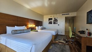 A hotel room with two beds, a desk with a phone and a digital clock, and a mirror. - Cute Studio in Palms at Waikiki (Honolulu)