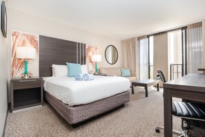 Une chambre d’hôtel avec un grand lit, un bureau, une chaise, une table de chevet, une lampe et un miroir.