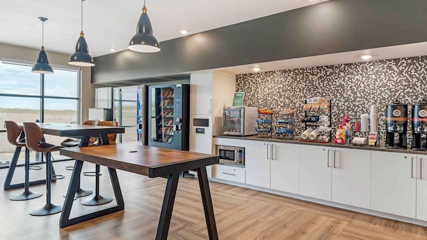 Una cocina moderna con una mesa de madera, taburetes de bar, lámparas colgantes, una estación de café y vistas a la playa.