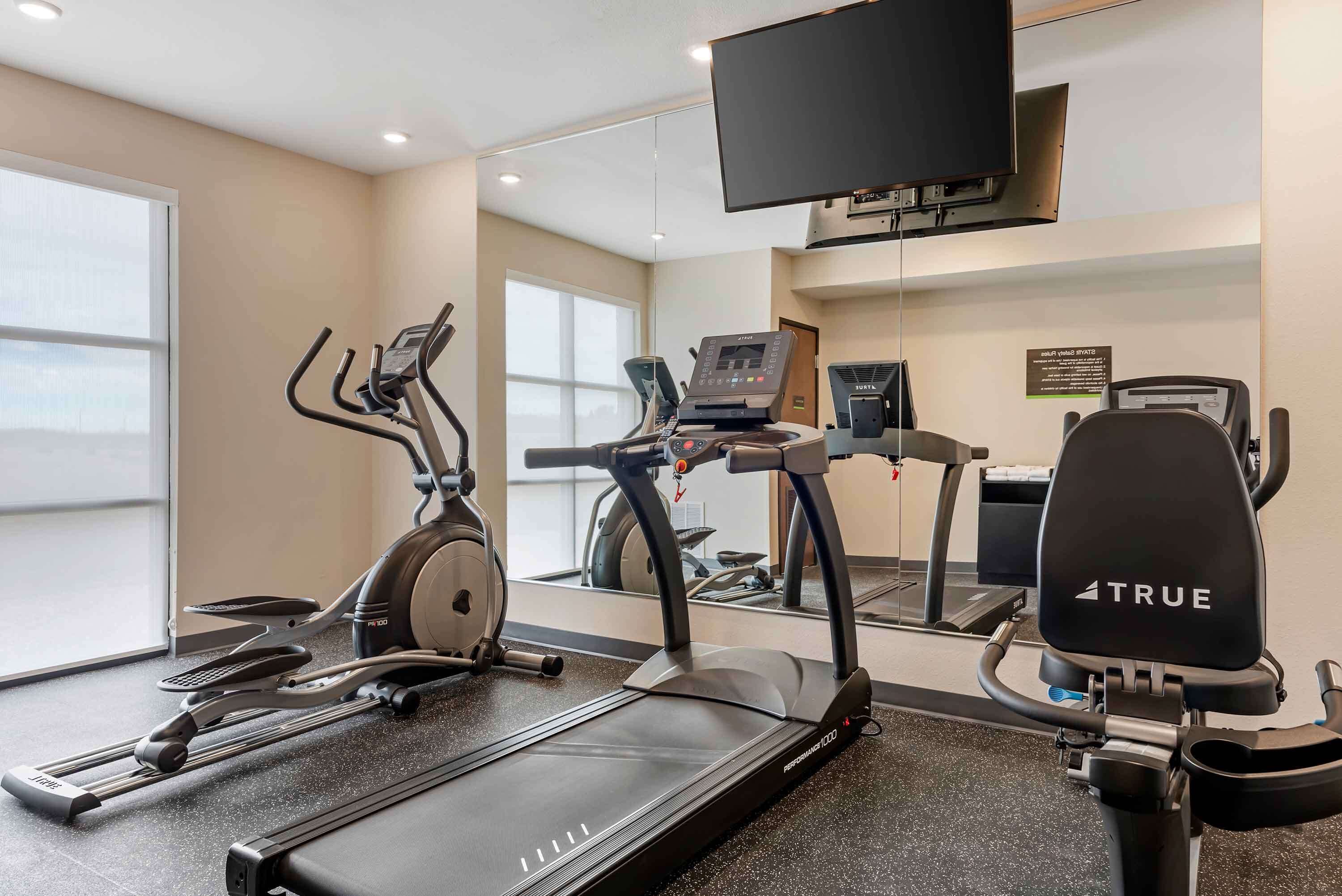 Un gimnasio con cintas de correr, elíptica y bicicleta estática.