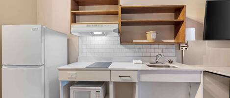 A compact kitchen with a built-in microwave, a refrigerator, and a sink.