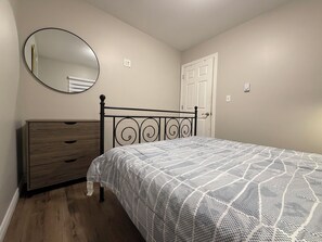 A bedroom with a bed, dresser, and a door.