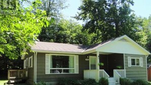 A single-story house with a front porch, a small deck, and a well-maintained lawn. - Point Clark Cottage Getaway (Huron Kinloss)