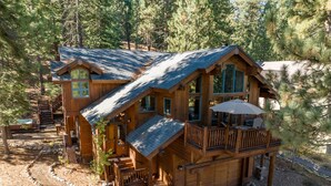 Eine Holzhütte mit einem Balkon, einer Whirlpoolanlage und einem gepflasterten Weg.