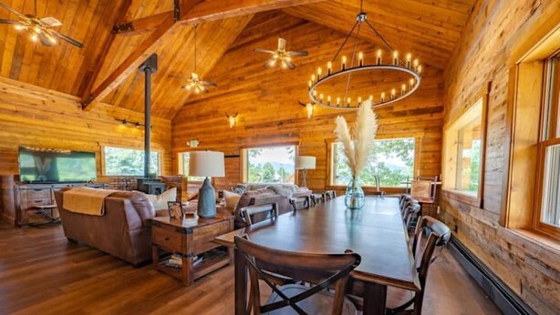 Une cabane en bois spacieuse, dotée d’une grande table à manger, de plusieurs coins salon et d’une cheminée.