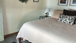 Une chambre à coucher avec un lit, une table de chevet, une lampe, un tableau encadré et une guirlande accrochée au mur.
