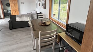 L’intérieur chaleureux d’un chalet comprend un coin repas, un canapé et une grande fenêtre donnant sur le paysage extérieur.