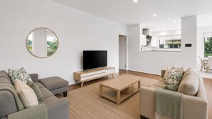 Una sala de estar moderna con televisor de pantalla plana, sofás, una mesa de centro y un espejo grande.