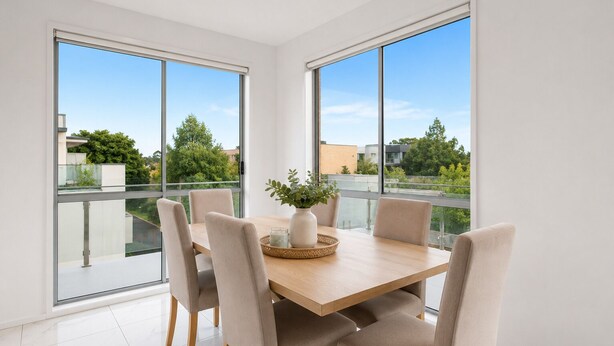 Un comedor moderno con una mesa de madera, sillas color beige y un florero con plantas.